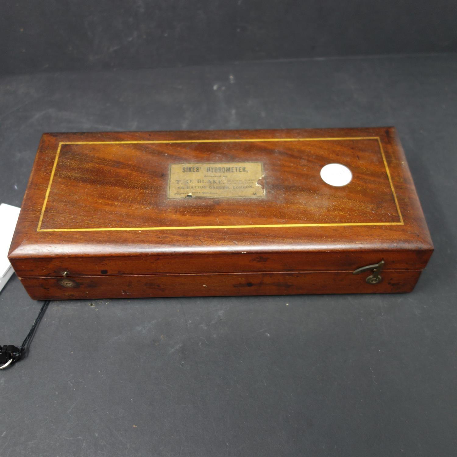 A cased Sikes' hydrometer, with brass weights, and thermometer marked 'W.R. Loftus, London W.', W.25