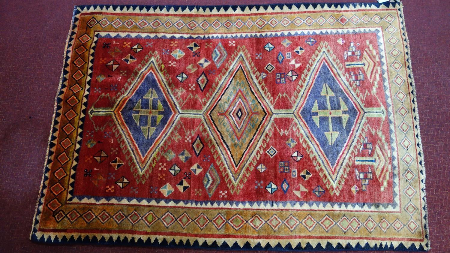 A Southwest Persian Qashqai rug, triple pole medallion with repeating petal motifs on a rouge field,