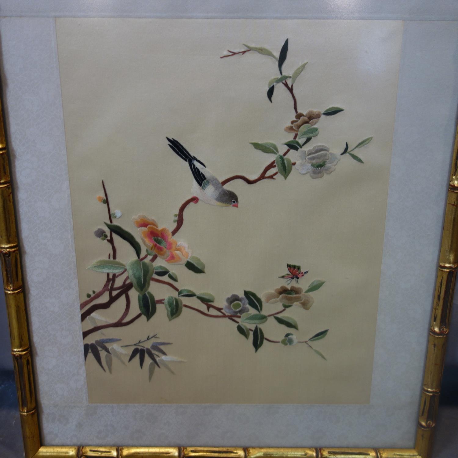 A Chinese embroidery on silk of a bird on a blossoming branch, in gilt painted bamboo design