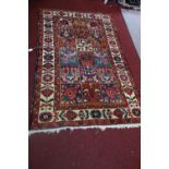 A Persian carpet, repeating panels depicting flowers, within floral border, 218 x 137cm