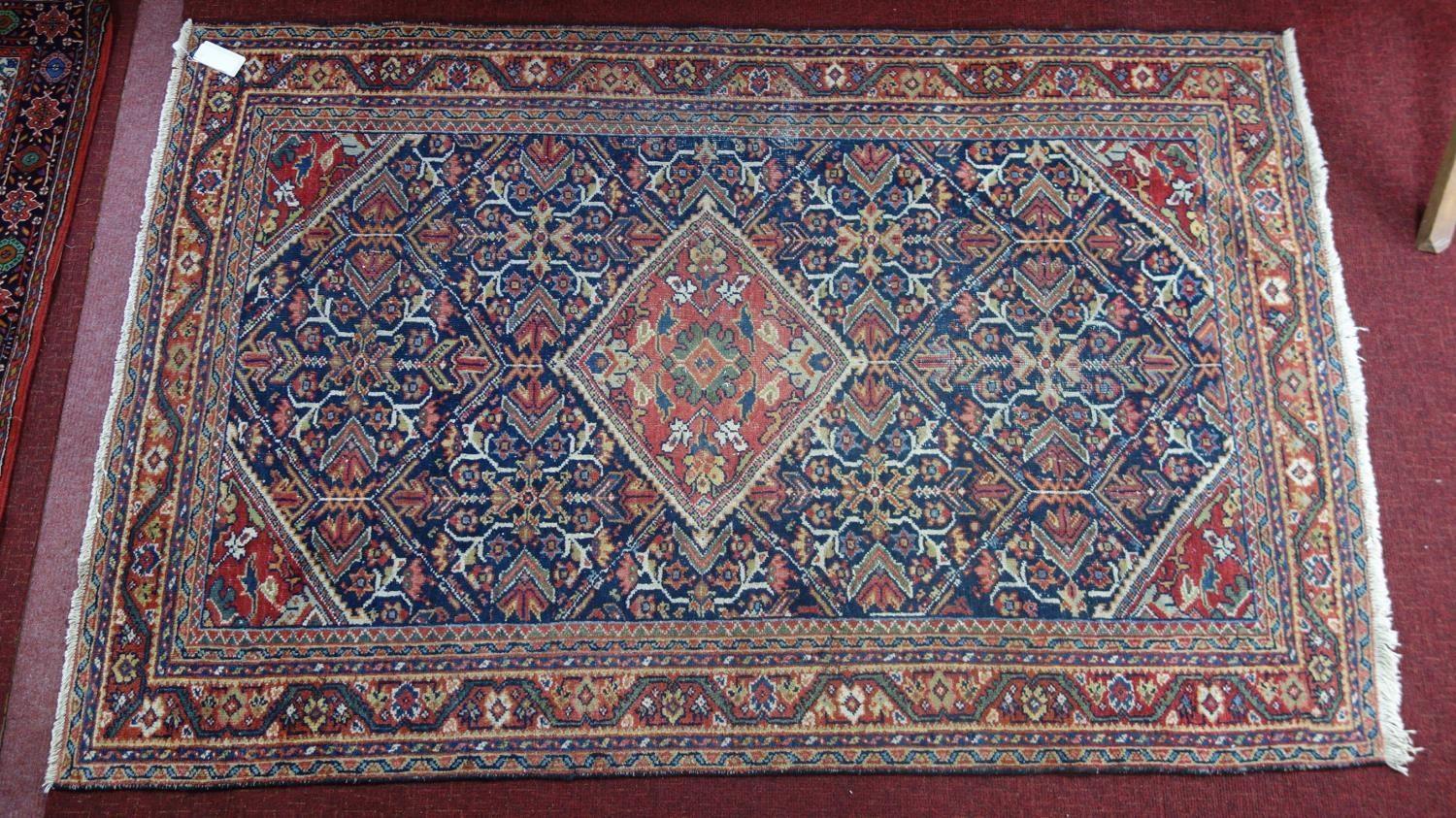 A Persian Qashqai rug, central diamond medallion and floral motifs on a dark blue ground, within