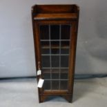 A narrow oak bookcase, with a leaded glass door, raised on bracket feet, H.99 W.36 D.21cm