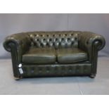 A two seater Chesterfield sofa, with green leather stud bound button back upholstery, on bun feet