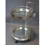 A contemporary silver painted circular two tier drinks trolley, with mirrored tops, raised on