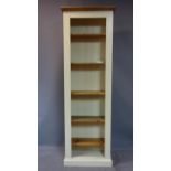 A cream painted pine bookcase, with moulded cornice, on pedestal base, H.198 W.66 D.30cm