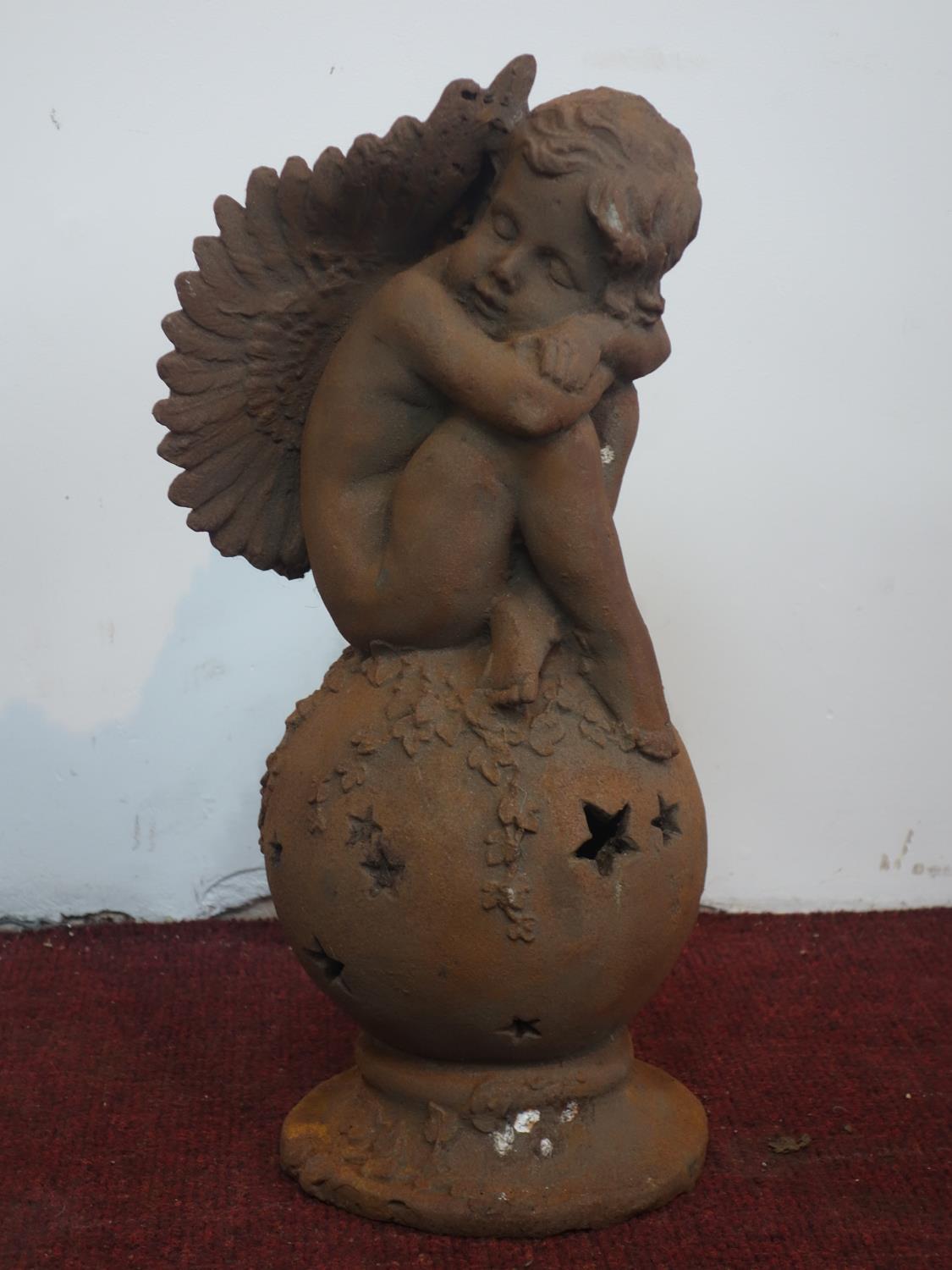 A cast iron cherub seated on a ball, H.49cm