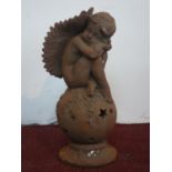 A cast iron cherub seated on a ball, H.49cm