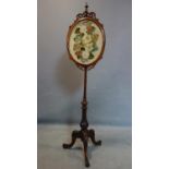 A late 19th century mahogany stand with tapestry screen depicting flowers, on three carved feet, H.