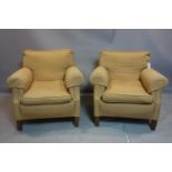 A pair of armchairs with beige upholstery, raised on tapered oak feet