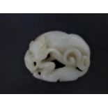 A 19th century Chinese white jade carving of a mythical beast and offspring, with pierced