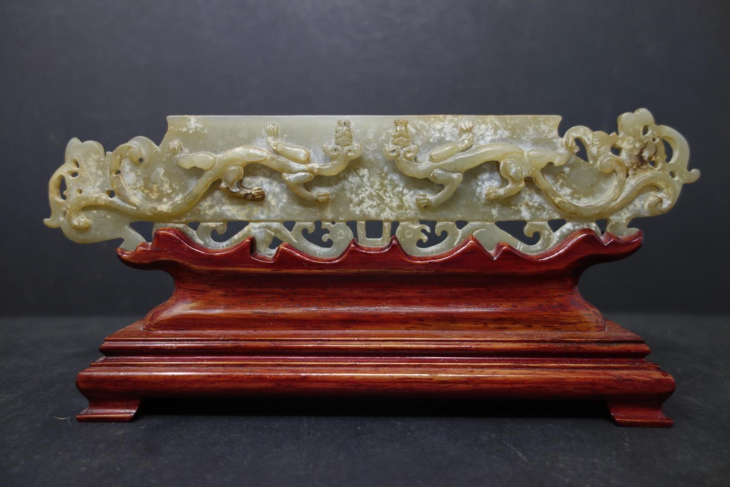 A 20th century Chinese jade tablet of 2 mythical beasts, 5 x 22cm, with fitted hardwood stand