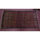 A Northeast Persian Meshad Belouch rug, repeating stylised tekkeh motifs on a rouge field within