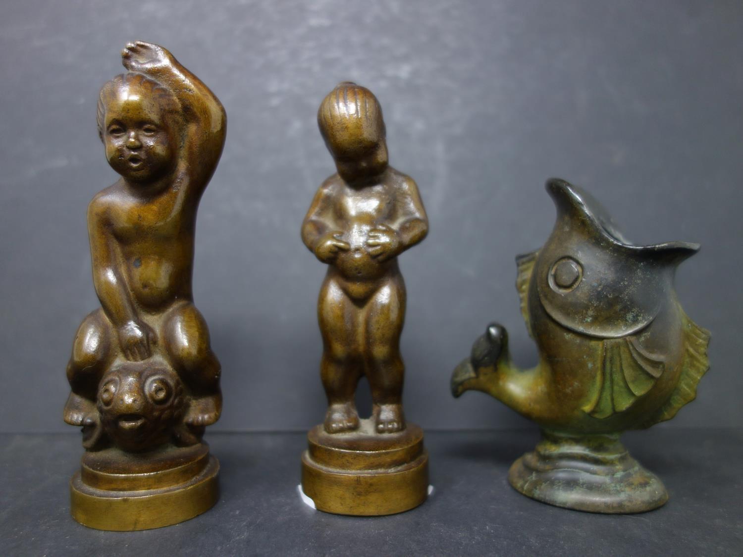 Two bronze cherubs, H.11.5cm, together with a cast metal fish vase, H.9cm