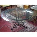 A large wrought iron garden table with glass top, H.73 D.150cm