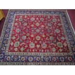 A Persian Tabriz carpet, having floral motifs on a rouge ground, within blue floral border, 332 x