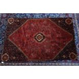 A Persian Qashqai carpet with geometric motifs, on a red ground, contained by geometric border,