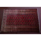 A 20th century Bokhara rug with repeating gull motifs, on a red ground, contained by geometric