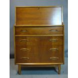 A teak bureau with drop flap above four drawers, on tapered feet, H.107 W.76 D.41cm