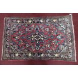 A Persian Meshad rug, central medallion and floral motifs on a rouge ground, within floral border,