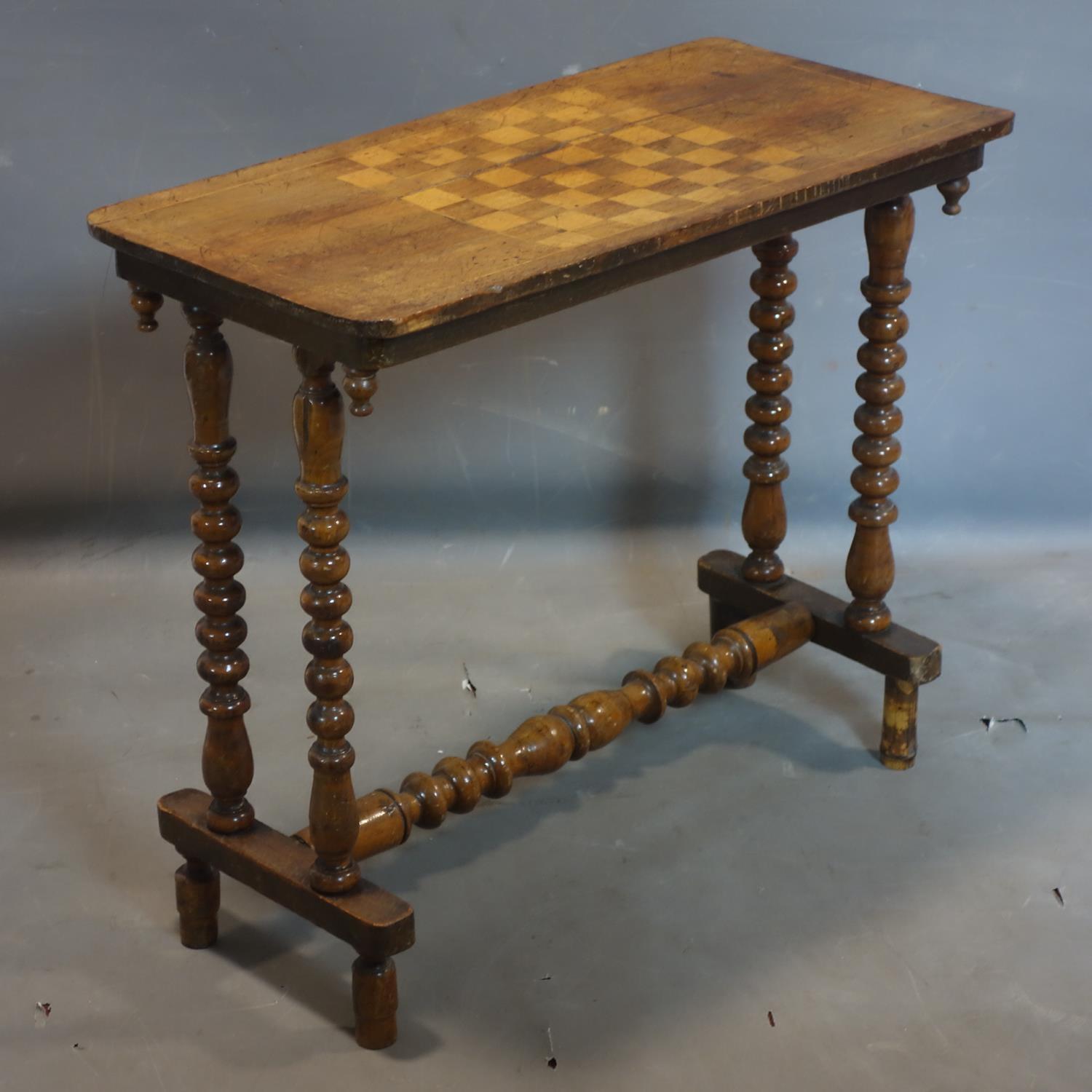 A Victorian walnut games table, raised on bobbin supports, H.67 W.76 D.38cm