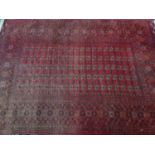 A large Persian Bokhara carpet, with repeating elephant pad motifs on a rouge ground within