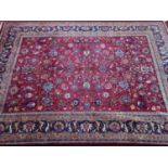 A signed Northeast Persian Meshad carpet, all over floral motifs on a pomegranate field, within