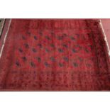 A Turkoman rug, with repeating elephant pad motifs on a rouge ground, within geometric borders,