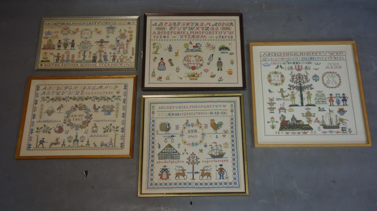 A collection of five 20th century Danish needlework samplers, with alphabets, numbers, figures,