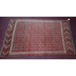 An Persian Bokhara rug, repeating gul motifs on a rouge field, within geometric borders, 280 x 165cm