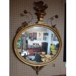 A Regency carved giltwood mirror, with eagle and floral surmount, having oval glass plate, 100