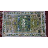A part silk Persian Kirman rug, geometric and animal motifs on a light pink/cream ground, within