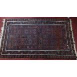 A 20th century Afghan rug with geometric designs, on a blue ground, contained by geometric border,