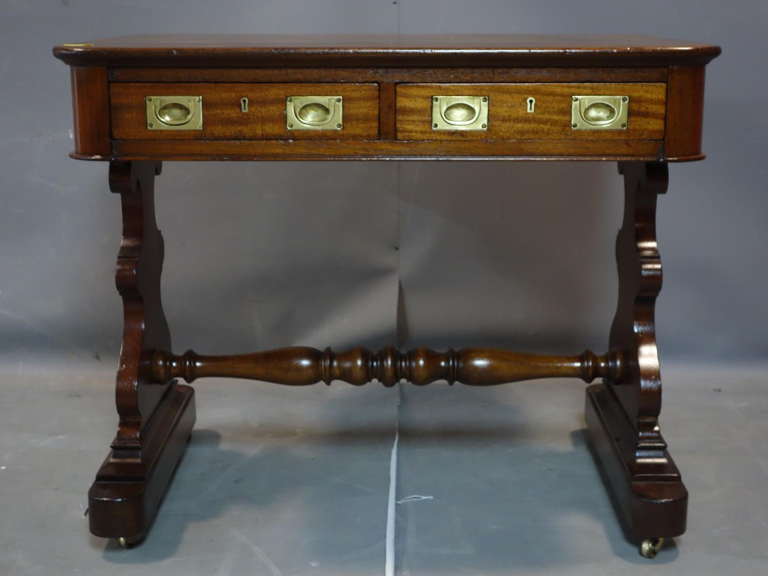 A 19th century mahogany campaign writing table with two drawers, on trestle supports and castors,