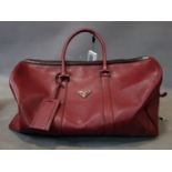 A Prada burgundy leather holdall bag. L.50cm