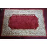 A Chinese woollen rug, rouge field to center within cream and gilt floral border, 181 x 122cm