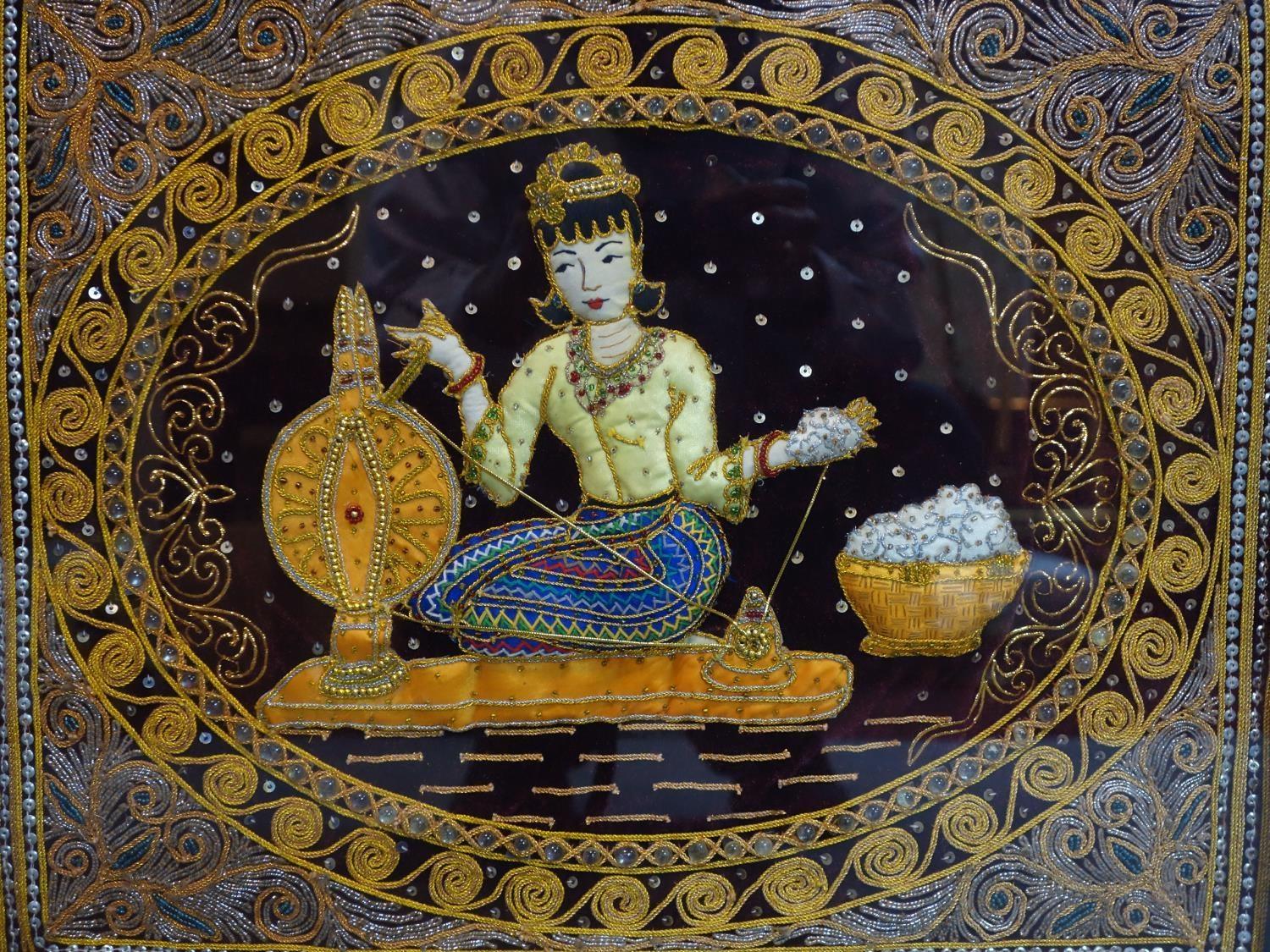 A Thai Kalaga textile depicting a seated lady spinning silk, in frame, 55 x 64cm