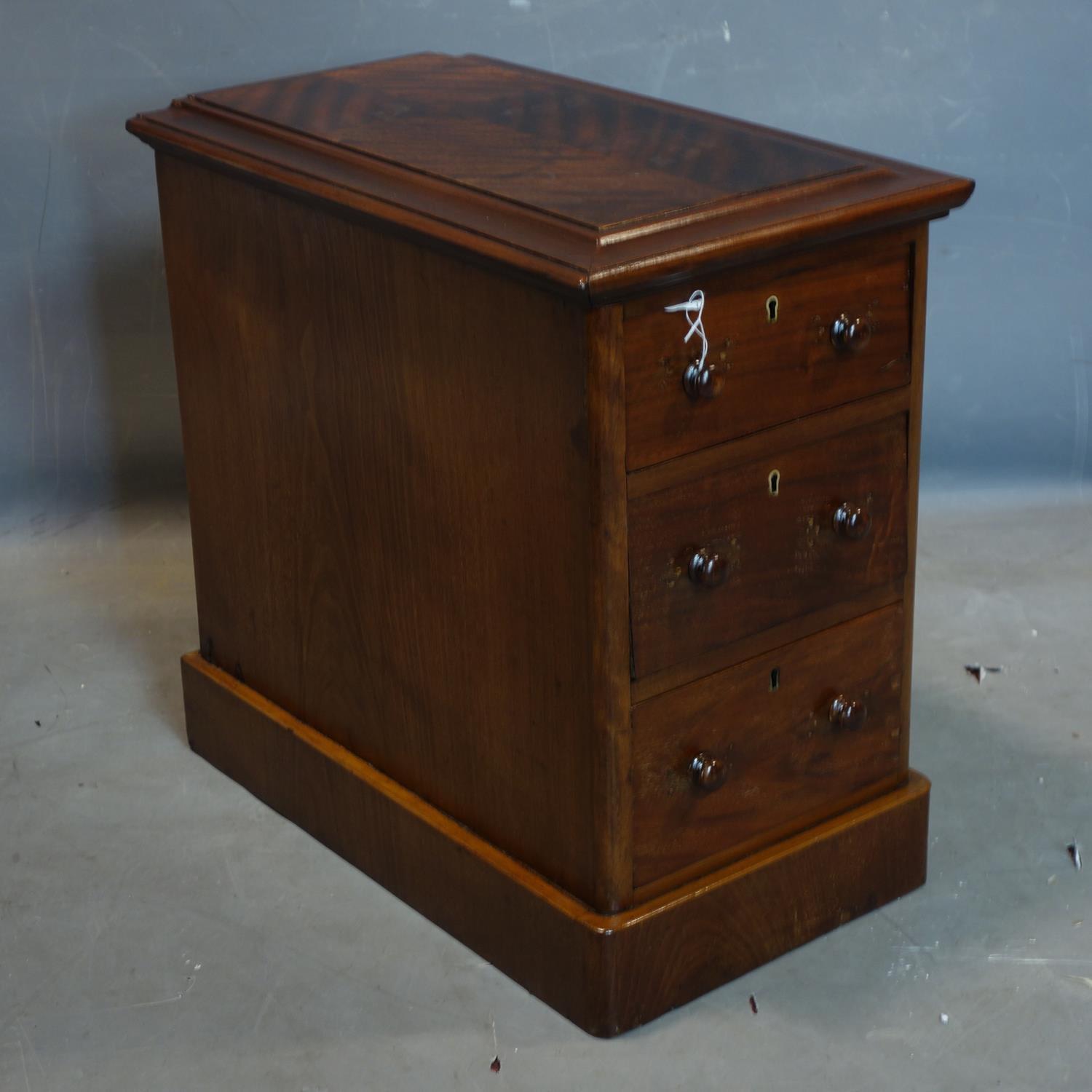 A mahogany pedestal chest of three drawers, with quarter veneered and moulded top, raised on
