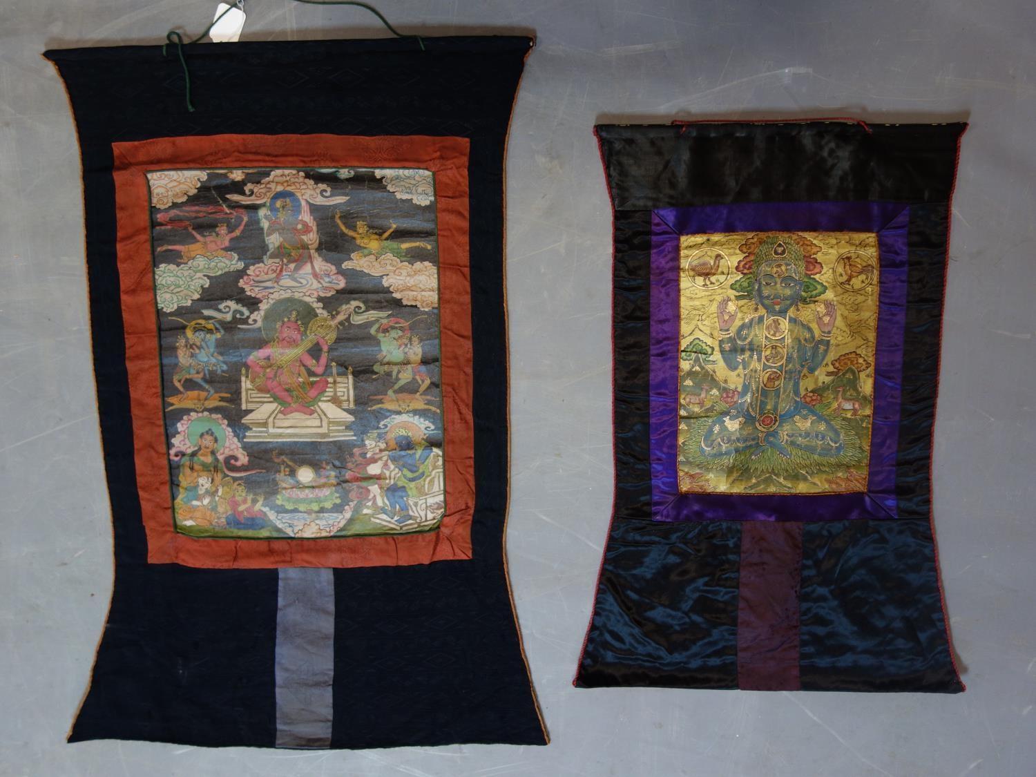 A hand-painted Tibetan Thangka depicting a deity in a landscape scene with animals, having script to
