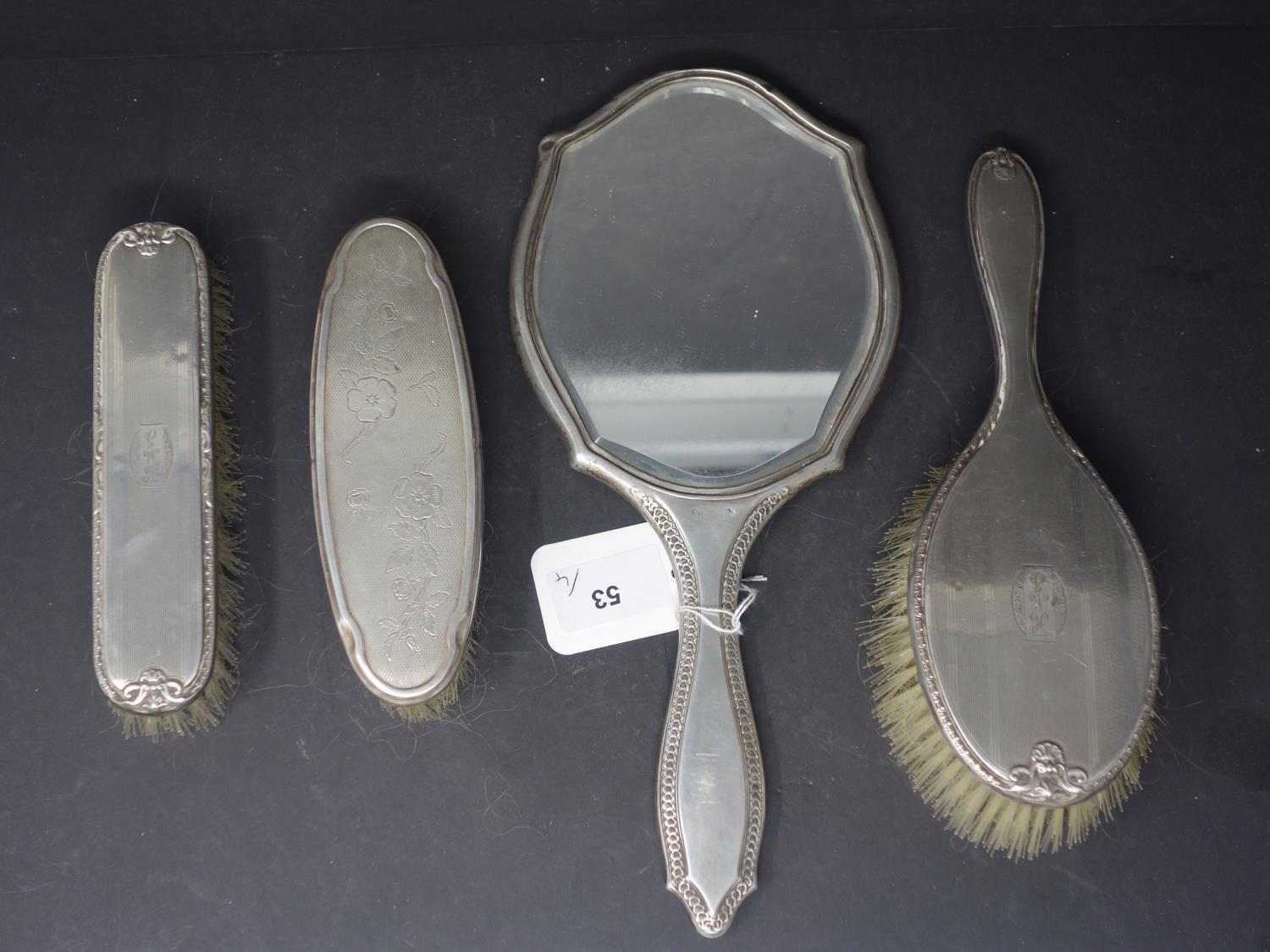 A silver dressing table mirror together with 3 silver dressing brushes