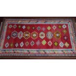 A South west Persian Qashqai Kilim, with repeating stylized diamond medallion, on a rouge field,