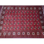 A North west Persian Turkoman carpet, the repeating stylized tekkeh motifs, on a rouge field,