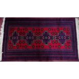 An Afghan Belouch rug with 4 geometric medallions, on a red ground, contained by geometric border,