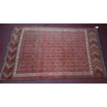 An Persian Bokhara rug, repeating gul motifs on a rouge field within geometric borders, 280 x 165cm
