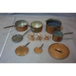 A collection of antique copper pans and measures