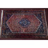 A Persian rug with central diamond medallion on a rouge field, within multi floral borders, 200 x