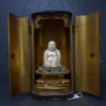 A 19th century Chinese ivory Buddha on carved gilt wood lotus base, set in lacquered shrine, H.15cm