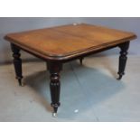 A Victorian mahogany wind out dining table, raised on reeded baluster legs and castors, with extra