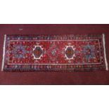 A Persian Heriz runner, with 5 geometric medallions, on a red ground, 173 x 65cm