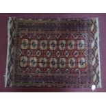 A 20th century Bokhara rug with repeating geometric gull motifs, on a red ground, contained by