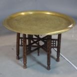 An Islamic brass tray top Bedouins table, with folding hardwood base, H.48cm Diameter 79cm
